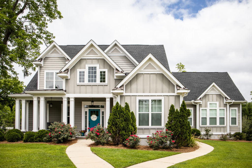 This is a single family home that is new construction cottage style house with hardy board and a partial metal roof. It is grey with a teal door and there is great curb appeal. The house has a double front entrance and it is on a large lot